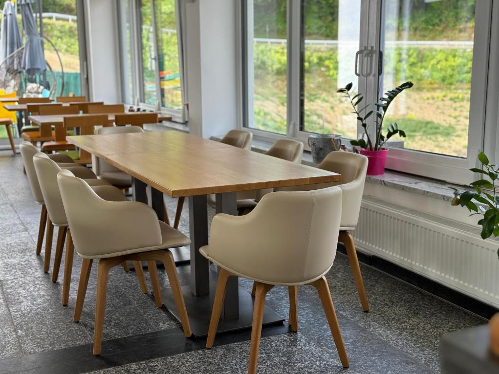 Restoran Hotela Pilot s dugim drvenim stolom uz staklene zidove